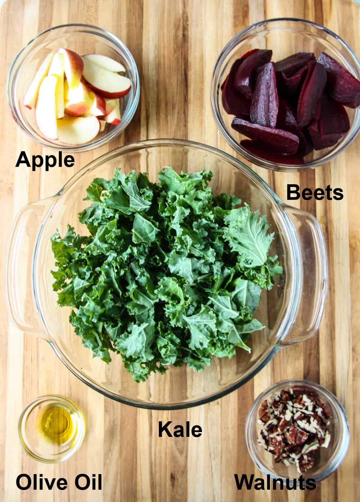 The ingredients to make this salad in glass bowls on a wooden board.