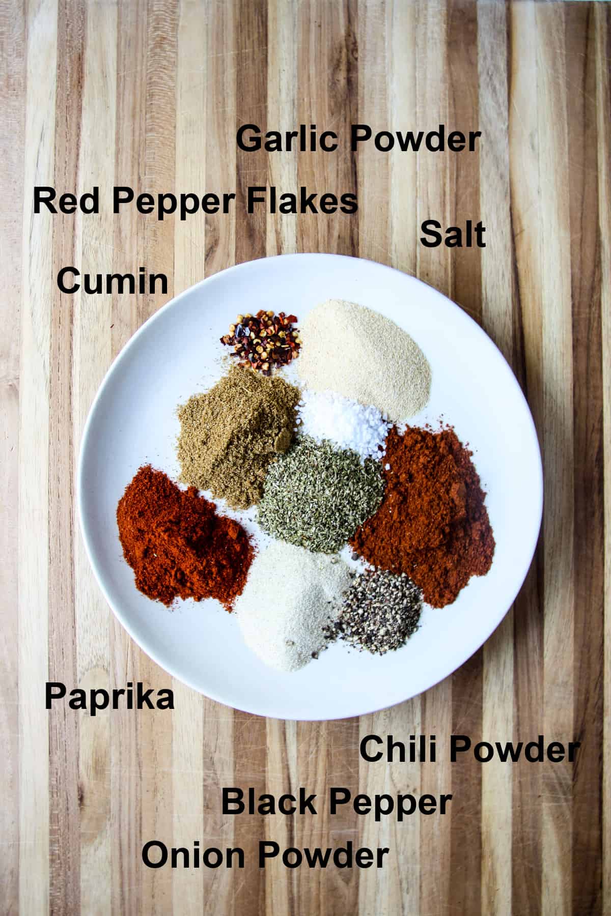 All of the spices used in this recipe on a white plate.
