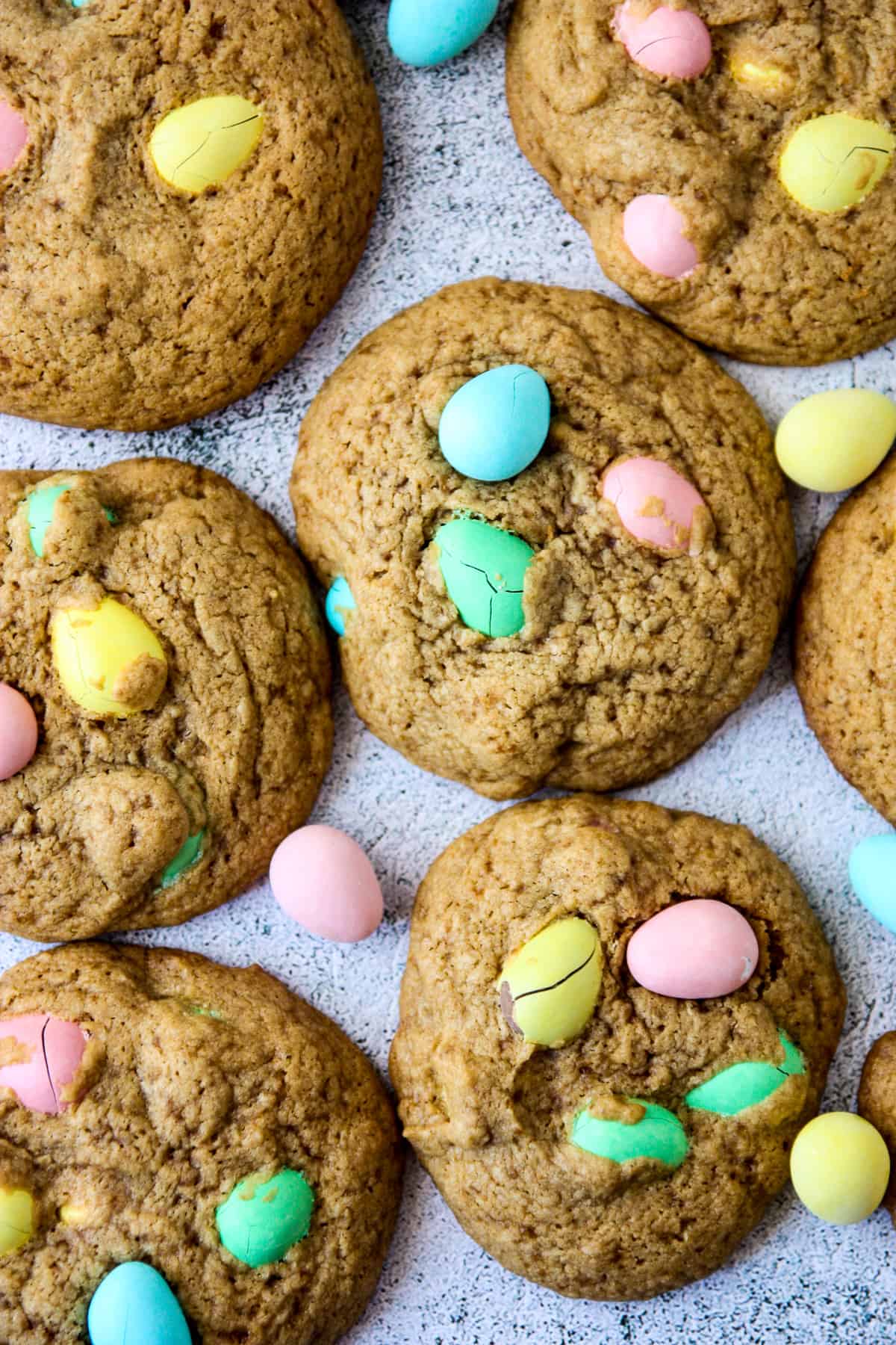 Cookies studded with colorful mini eggs, on a stone countertop.