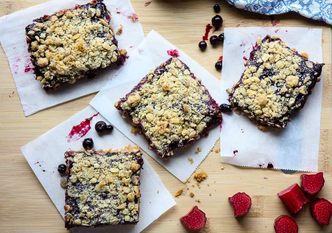 Four rhubarb blueberry oatmeal bars on  parchment paper.