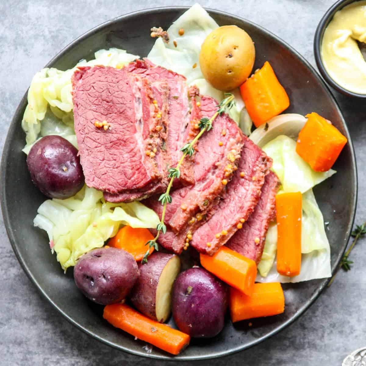 Corned beef and cabbage with potatoes and carrots on a black plate.