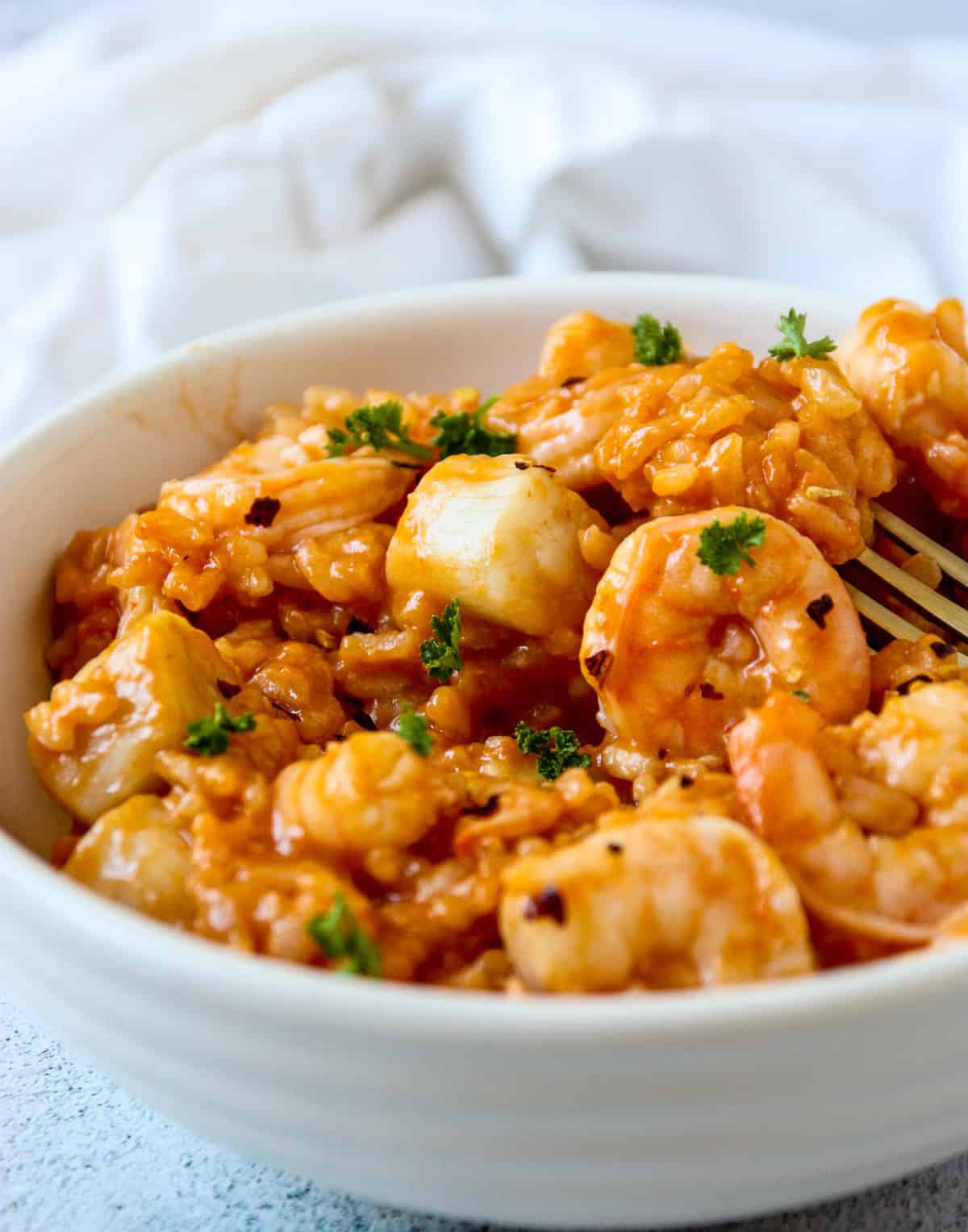 Risotto marinara in a white bowl with a silver fork.
