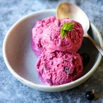 Three scoops of black currant ice cream in a light green dish.