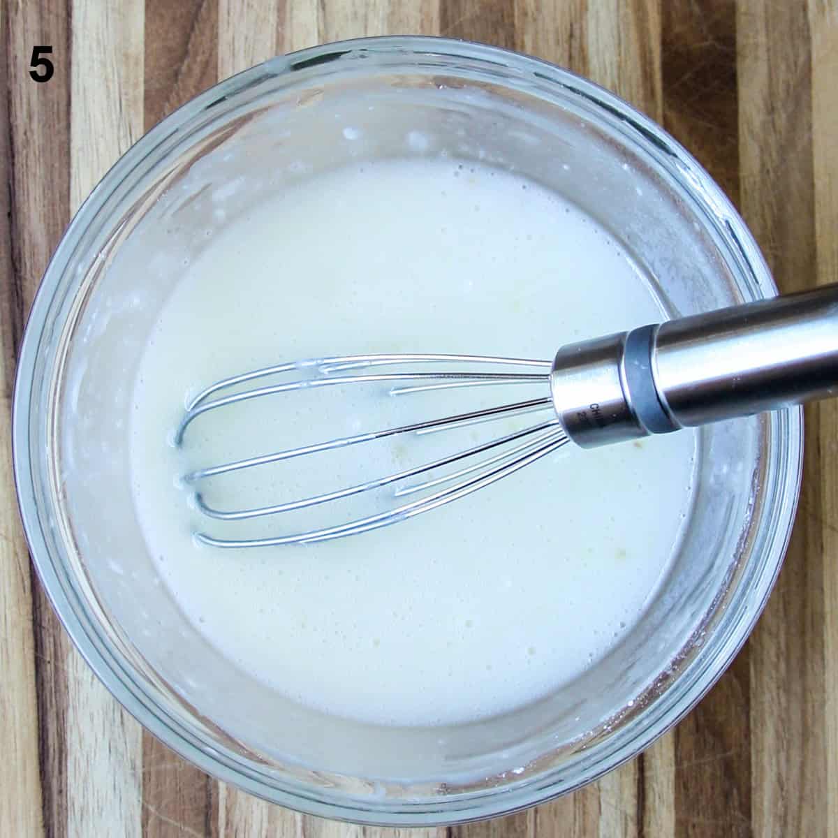 The lemon glaze being whisked in a glass bowl.
