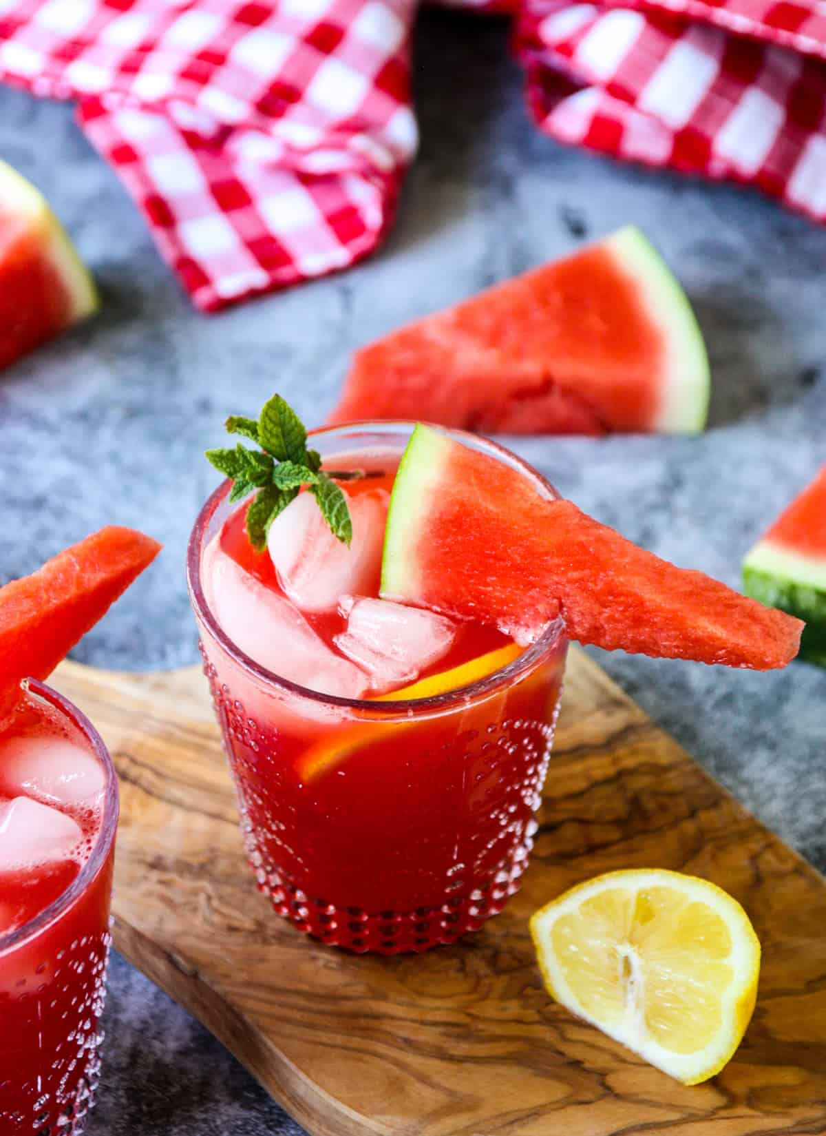 A vodka watermelon cocktail in a clear glass on a wooden board.