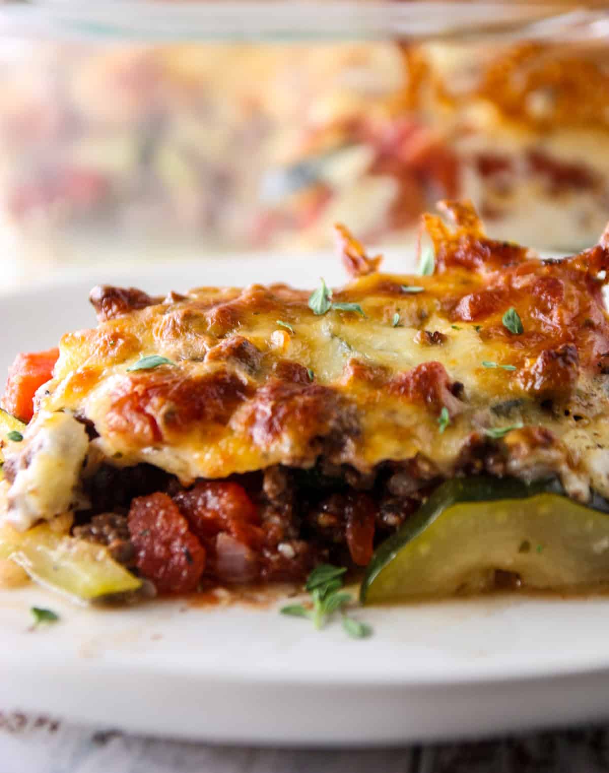 A slice of ground beef zucchini casserole on a white plate.
