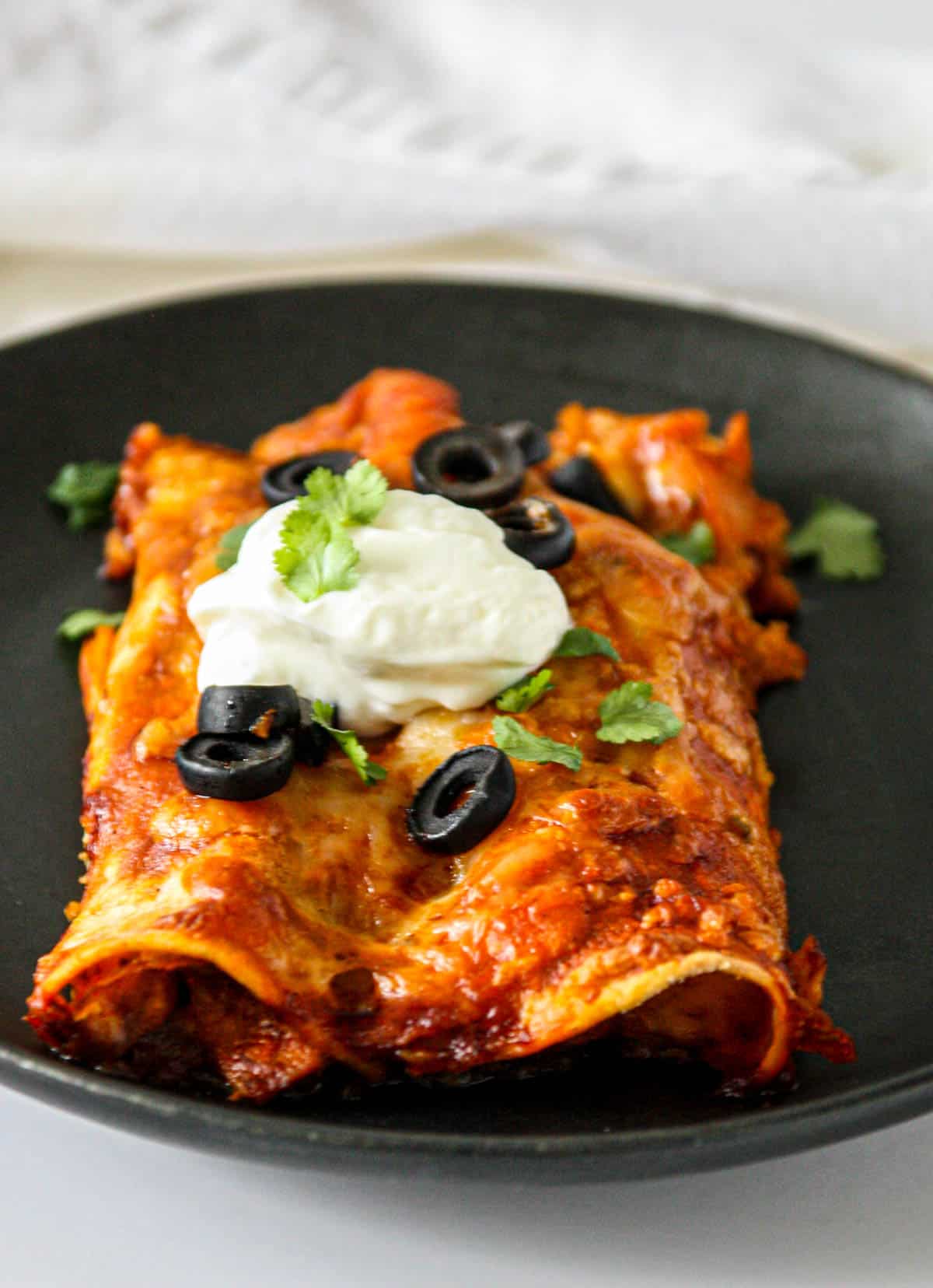 Two turkey enchiladas garnished with black olive slices.