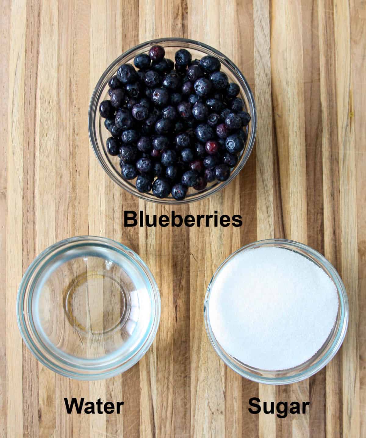 The ingredients for making blueberry simple syrup in glass bowls.